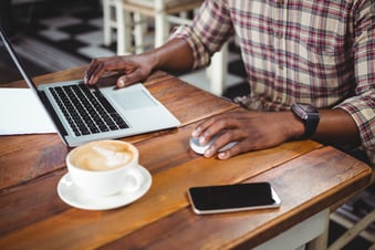 Mid-section of a man using laptop in cafeteria