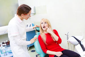 Closeup portrait sad girl, patient woman with painful tooth, ache siting in chair, medical office explaining her problem to dentist doctor isolated dental clinic background. Face expressions, feelings