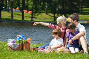 Happy young  family playing together with kids and eat healthy food  in a picnic outdoors
