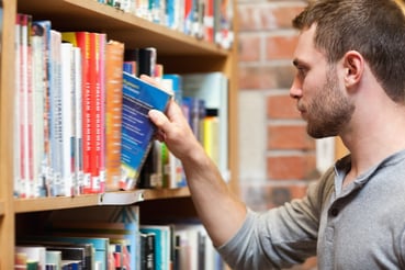 Male student picking a book in a library